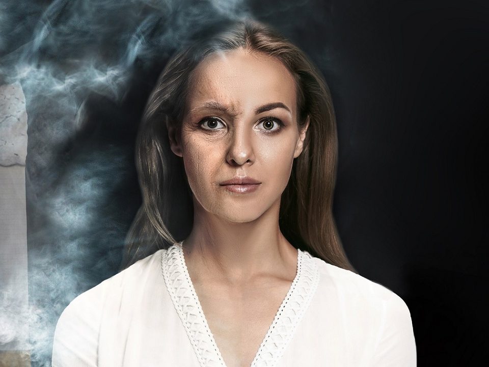 Mulher jovem com blusa branca que fuma e tem pele prejudicada