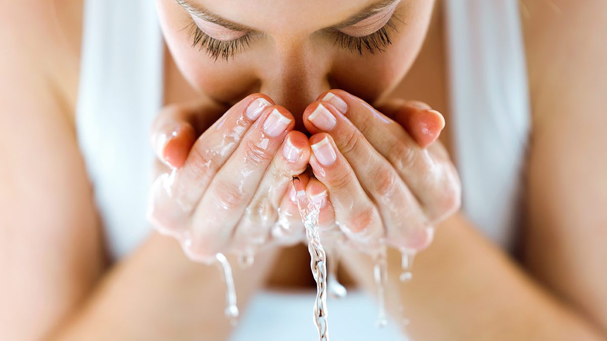 Mulher jovem limpa rosto com água