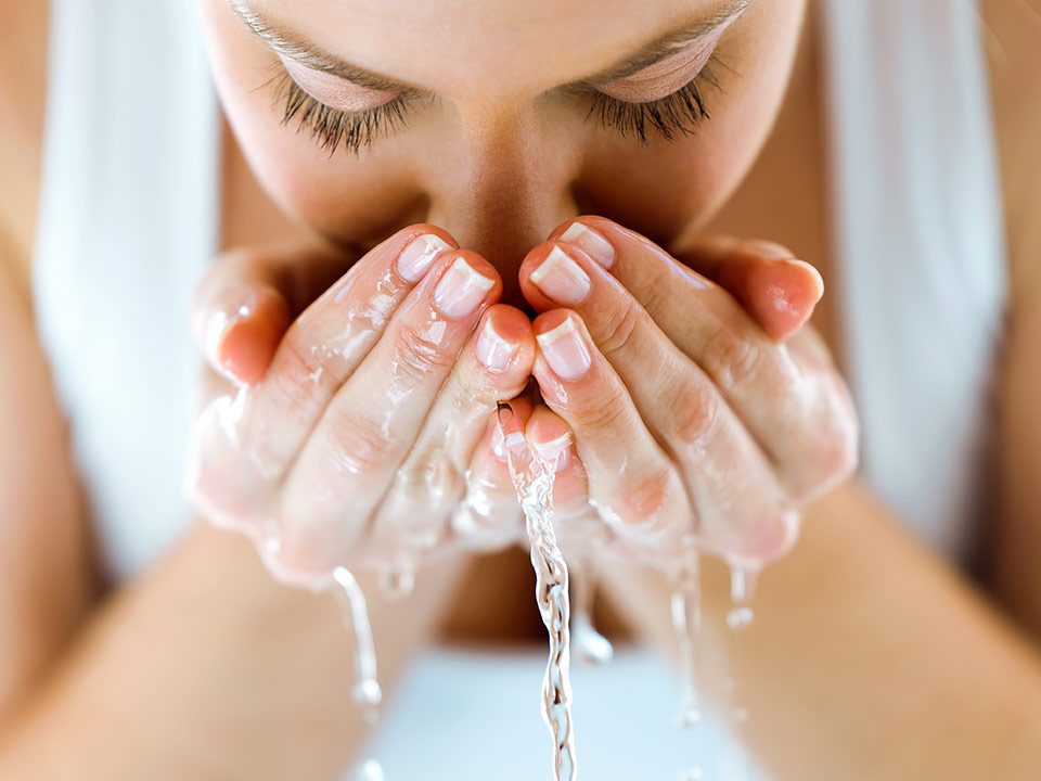 Mulher jovem limpa rosto com água
