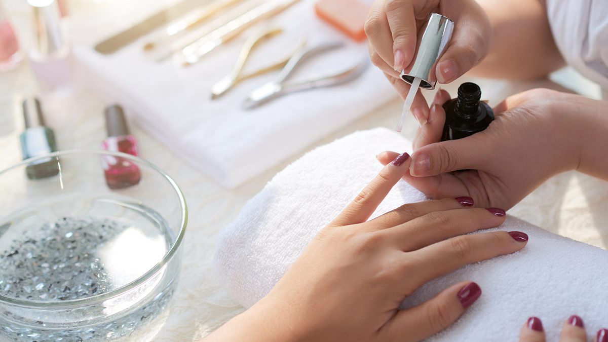 Mulher faz as unhas em salão de beleza com manicure