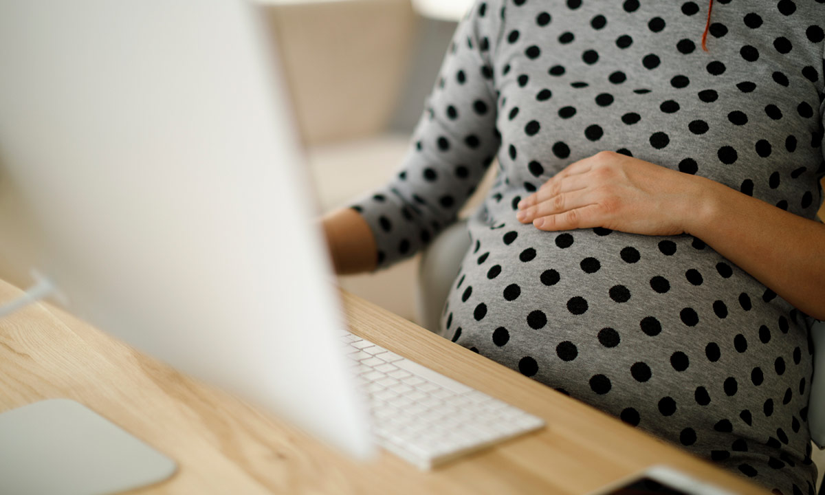 Mulher gestante sentada em frente ao computador