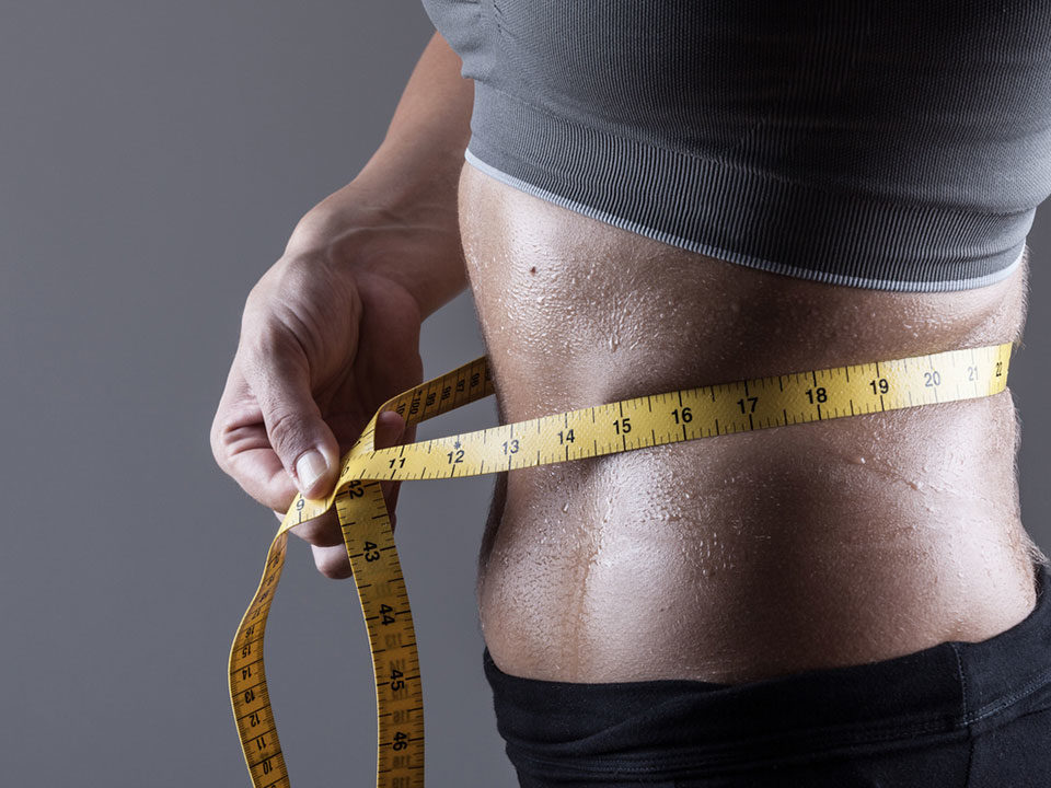 Mulher medindo circunferência abdominal com fita métrica