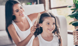 Mãe arrumando cabelo de filha com escova de cabelo