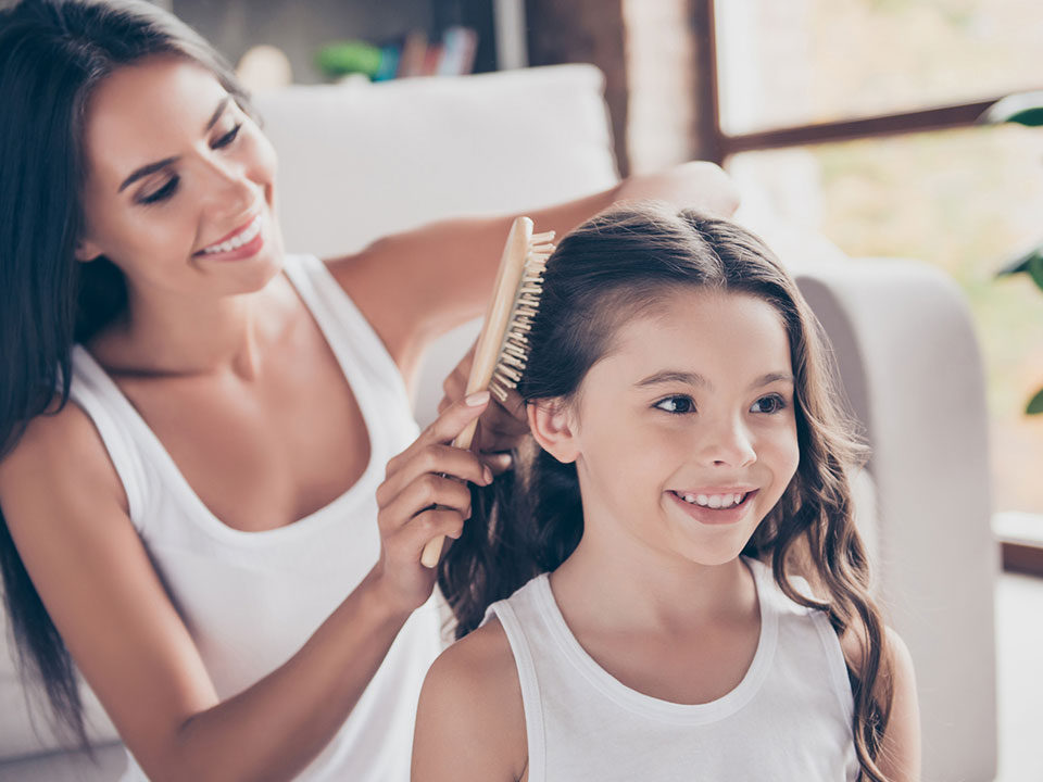 Mãe arrumando cabelo de filha com escova de cabelo