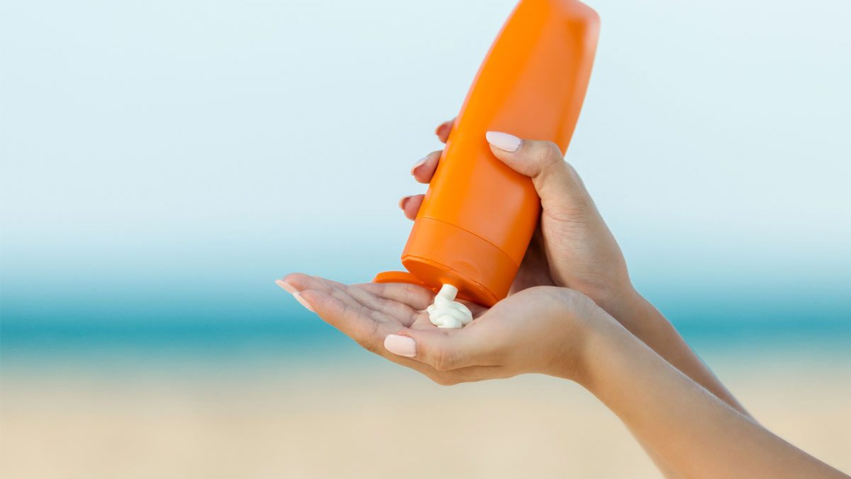 Protetor solar laranja com fundo de uma praia
