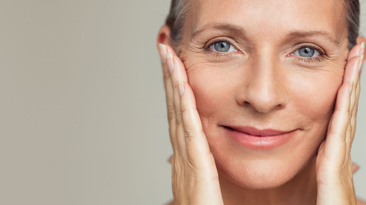 Mulher com mãos no rosto mostrando pele na fase da menopausa