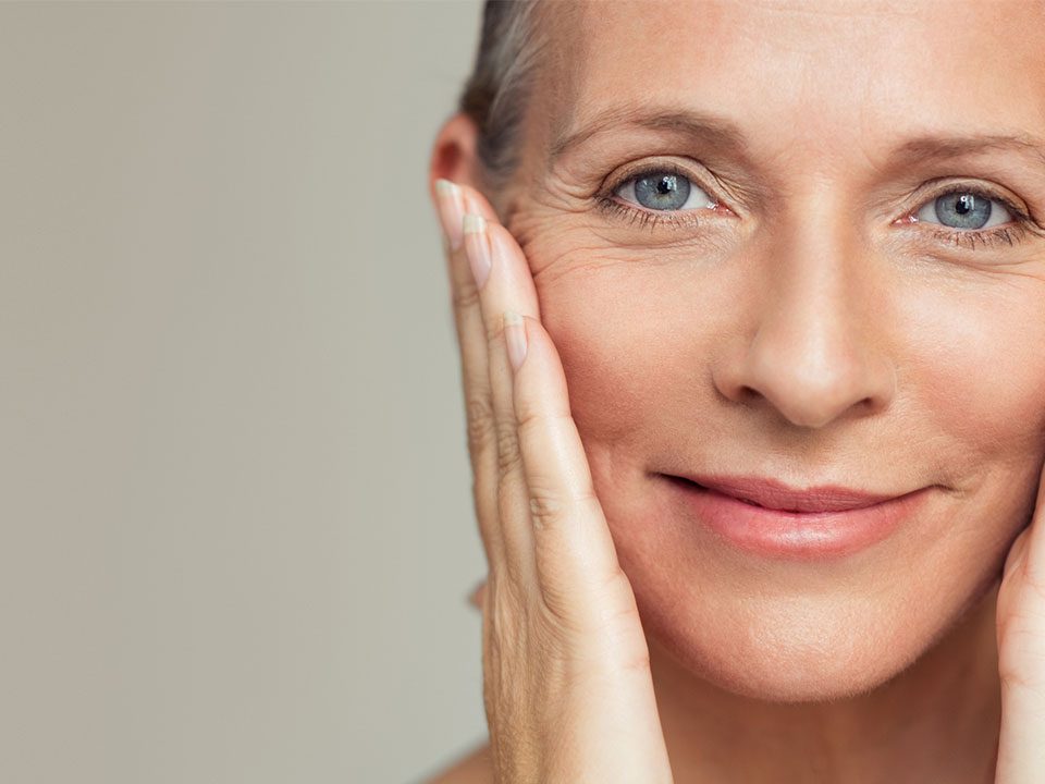 Mulher com mãos no rosto mostrando pele na fase da menopausa