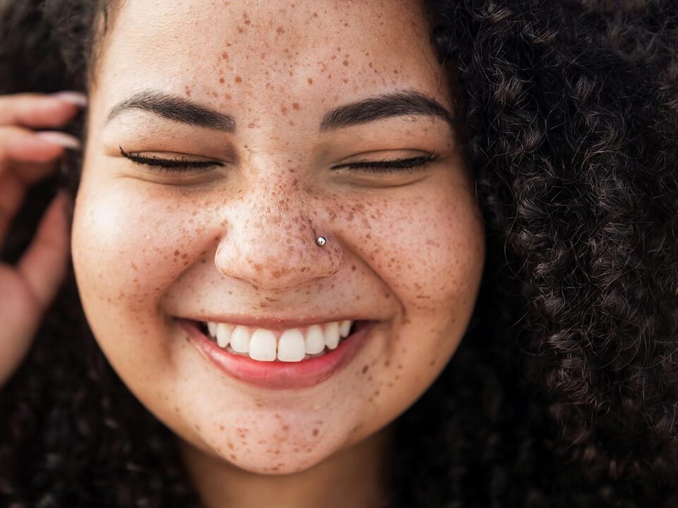 Menina sorrindo com um cabelo encaracolado com sardas no rosto