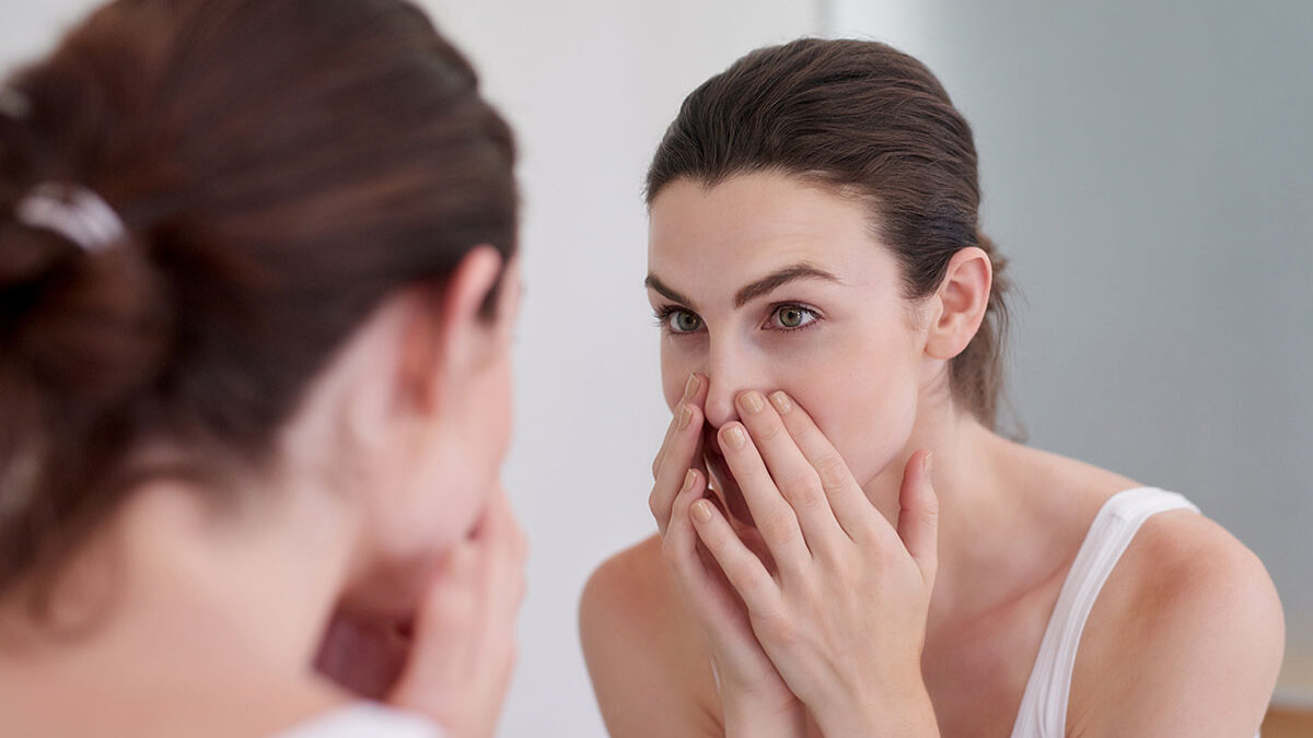 Mulher olhando a pele com oleosidade