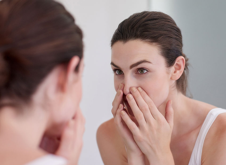 Mulher olhando a pele com oleosidade